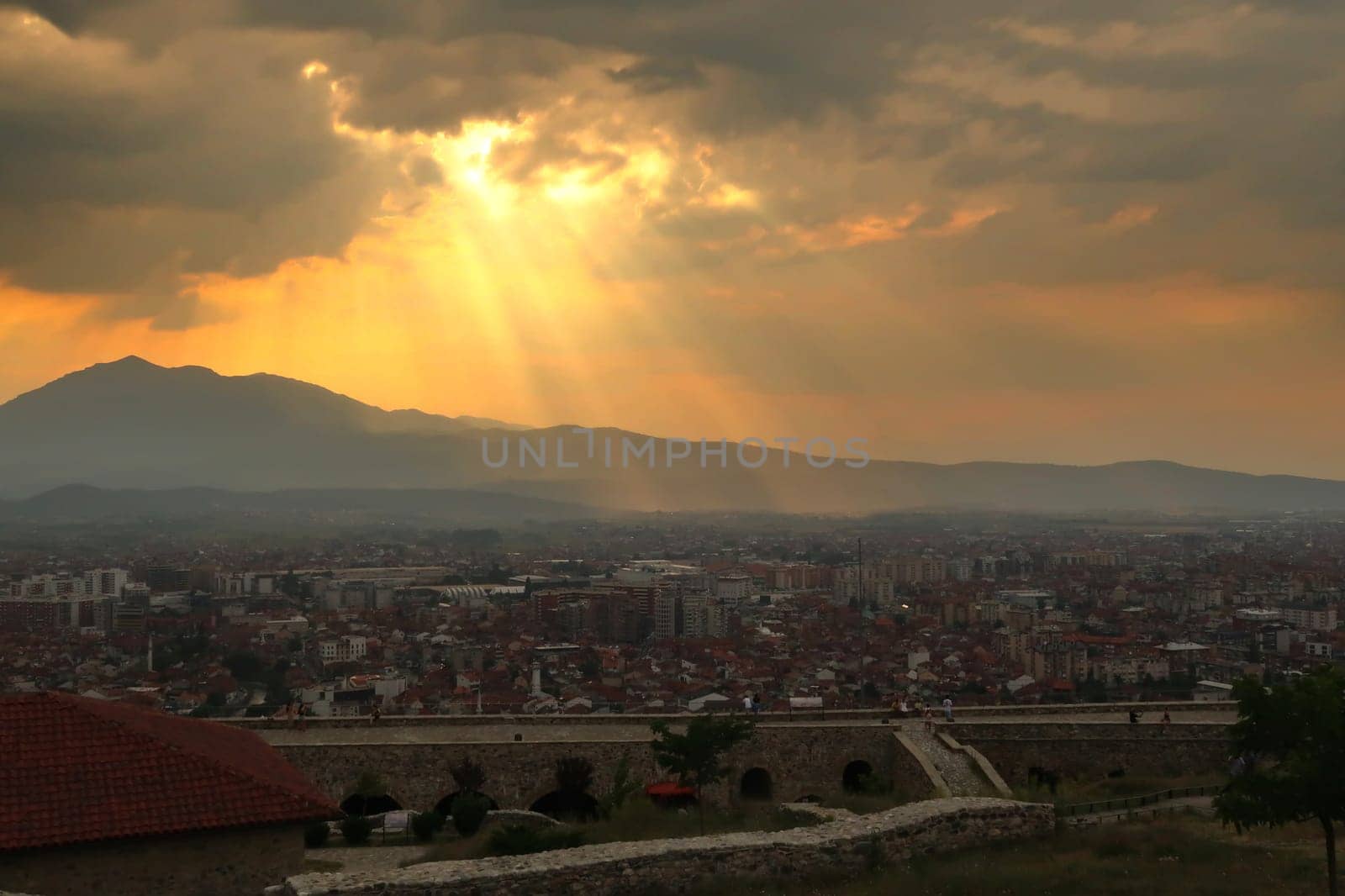 View from the Prizren Fortress before sunset, golden sunrays are breaking through the clouds of a spectacular sky, Prizren, Kosovo 2022