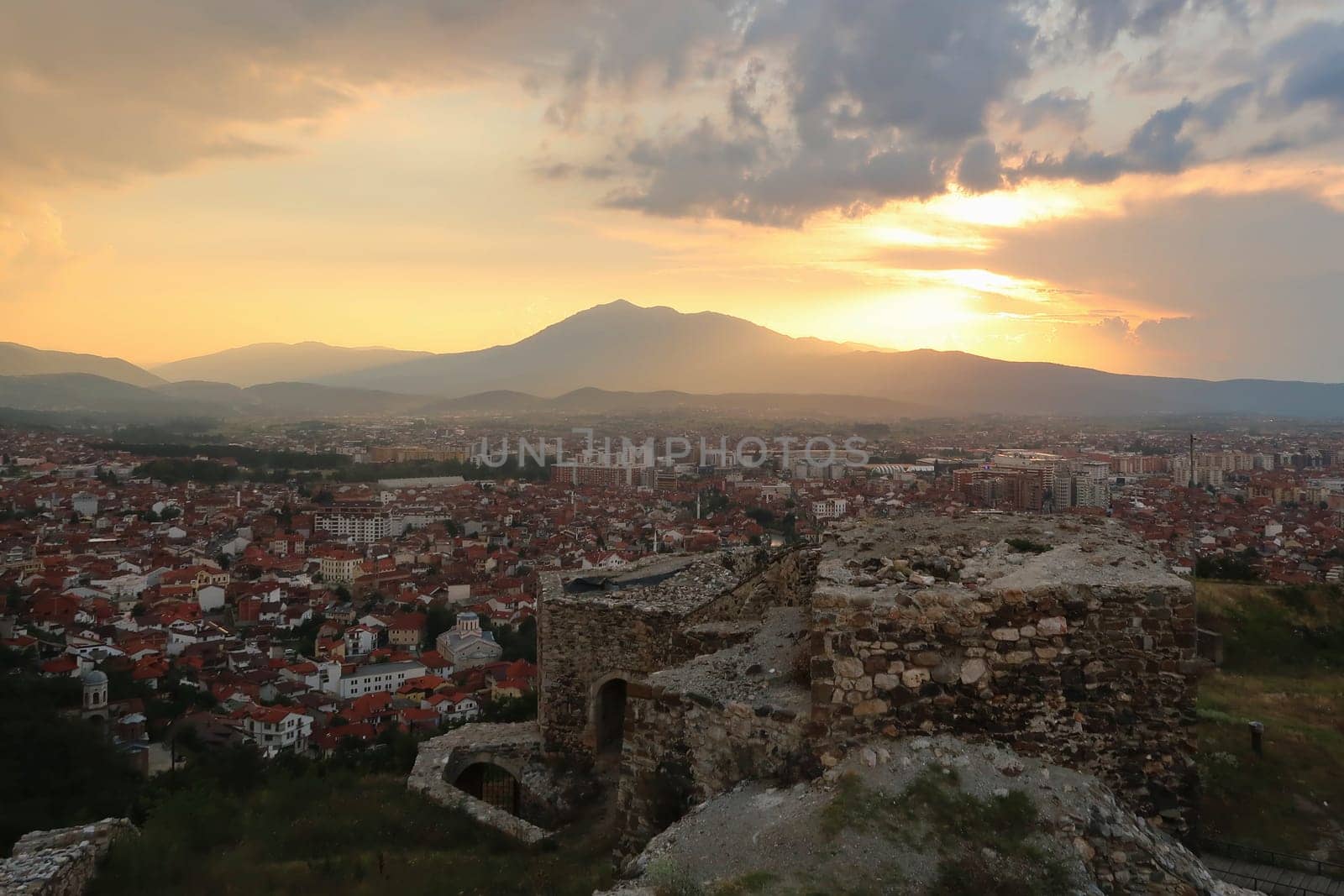 View from the Prizren Fortress at sunset, stone structure, ruins in the foreground and a colorful sky over the old town, city in the background, Prizren, Kosovo 2022