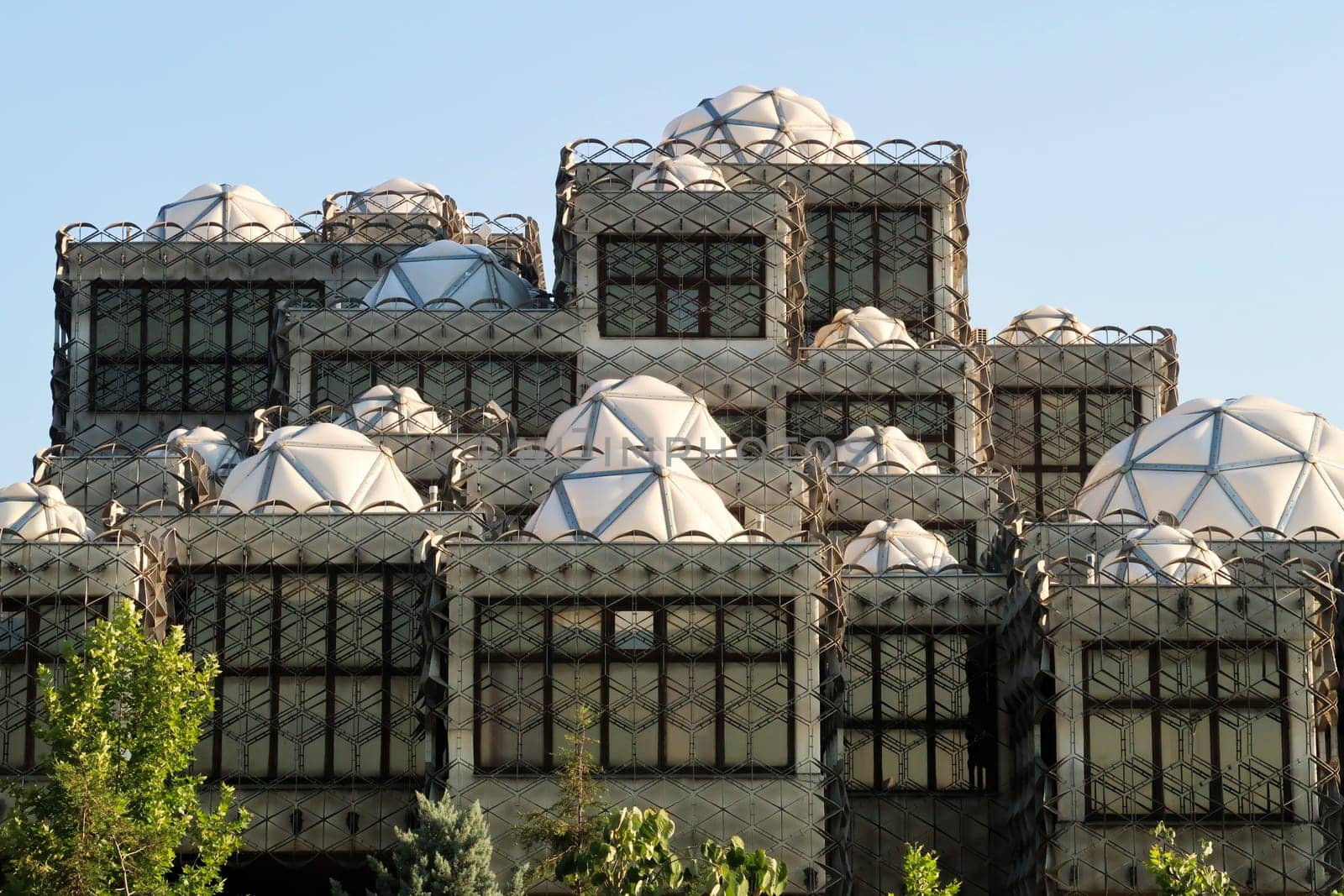 The facade of the National University Library of Kosovo, covered by a metal grid, net, many white domes with geometric pattern on top, an example of socialist, brutalist architecture in the city center of Prishtina, Pristina, Kosovo 2022