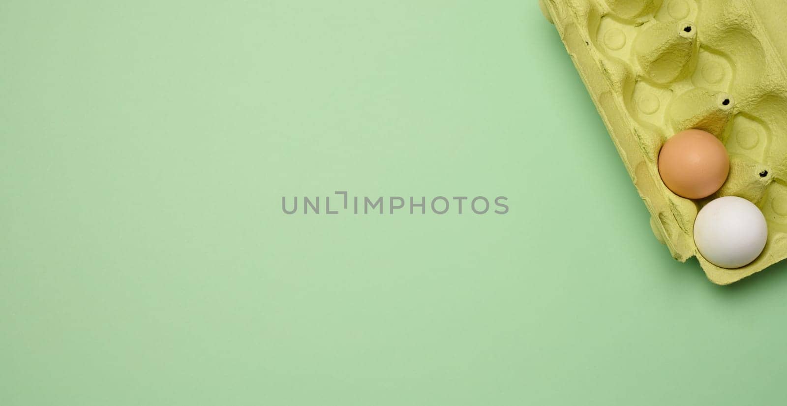 Chicken egg and paper storage box on green background, copy space
