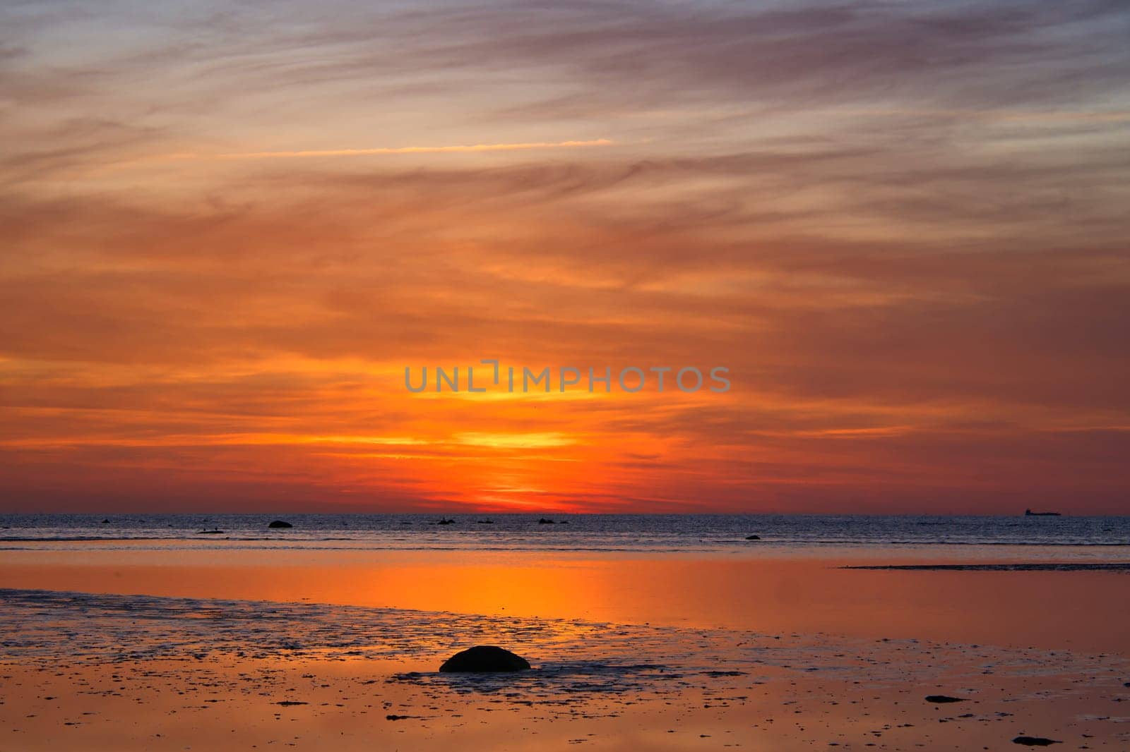 Sunset, illuminated sea. Sandy beach in the foreground. Light waves. Poel island on the Baltic Sea. Nature photo from the coast