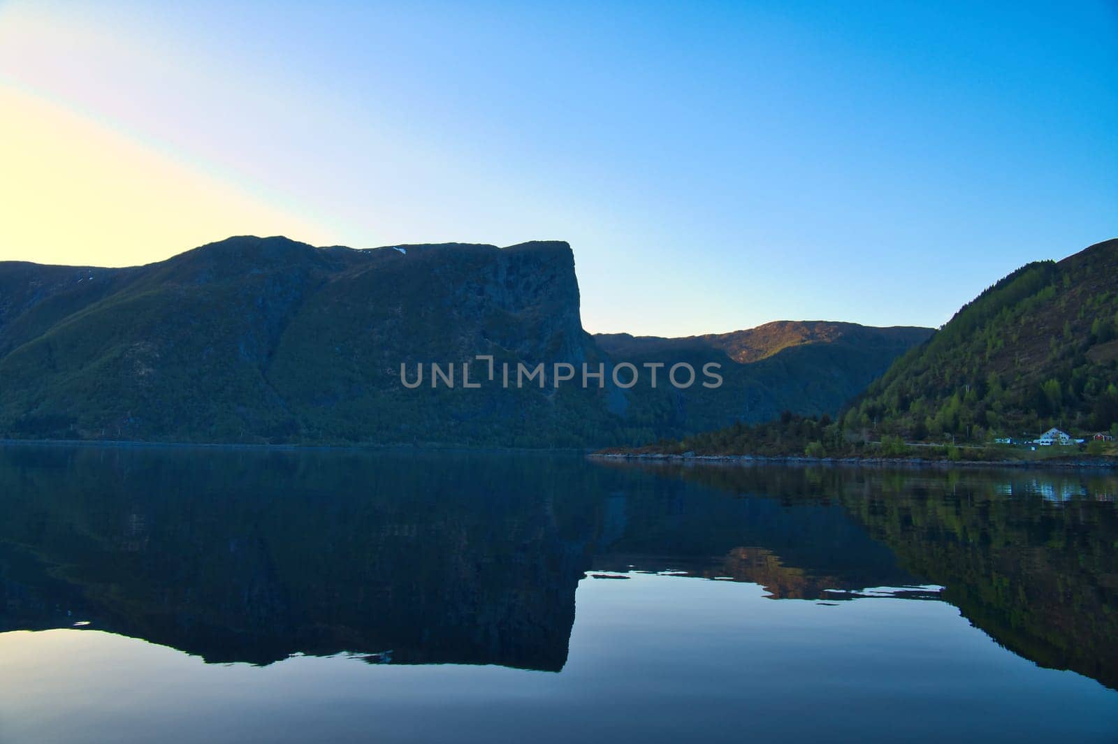 Norwegian fjord landscape. View of mountains with rugged vegetation. Crystal clear water in the foreground. Landscape from Scandinavia