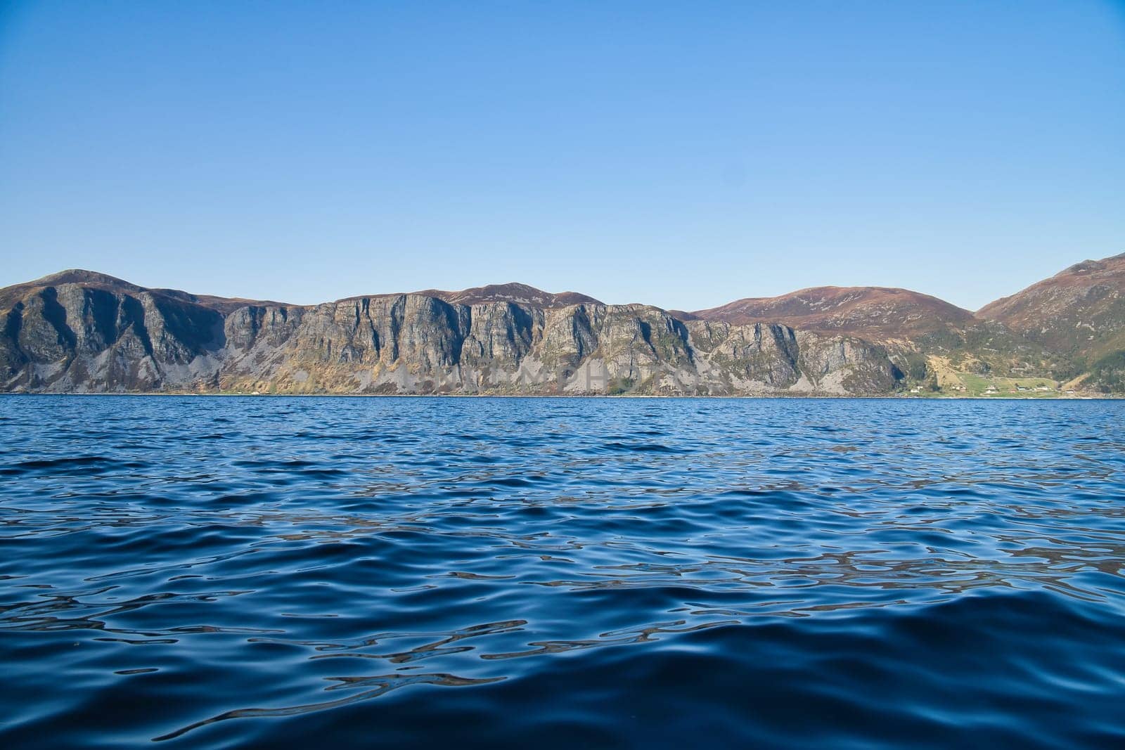 Norwegian fjord landscape. View of mountains with rugged vegetation. Crystal clear water in the foreground. Landscape from Scandinavia