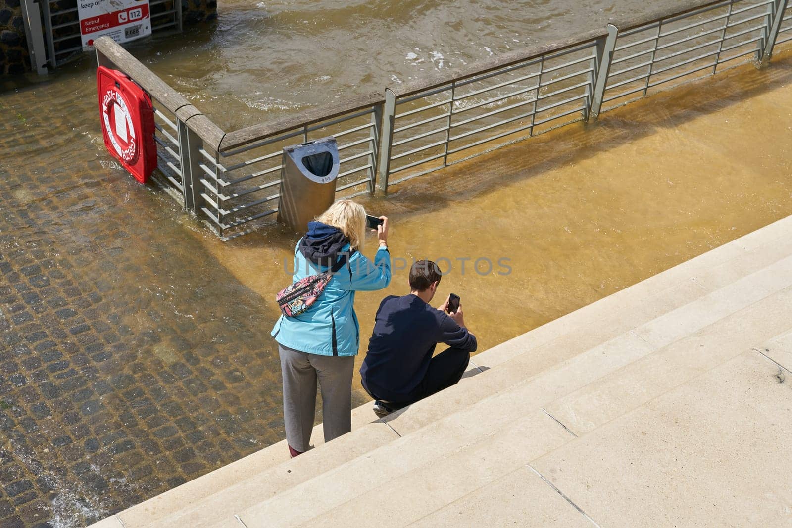 Tourists photograph the flood on the steps of the Rheinboulevard on the banks of the Rhine in Cologne