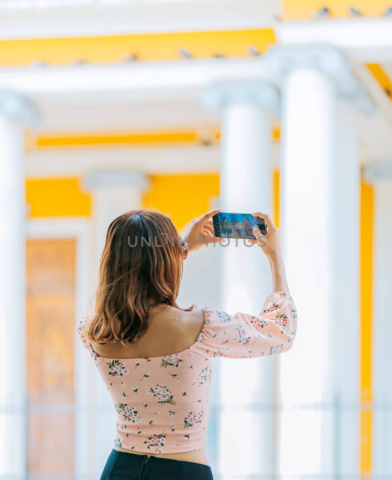 Young tourist taking photos of a tourist cathedral with cell phone. Girl taking photos of the Granada cathedral with cell phone