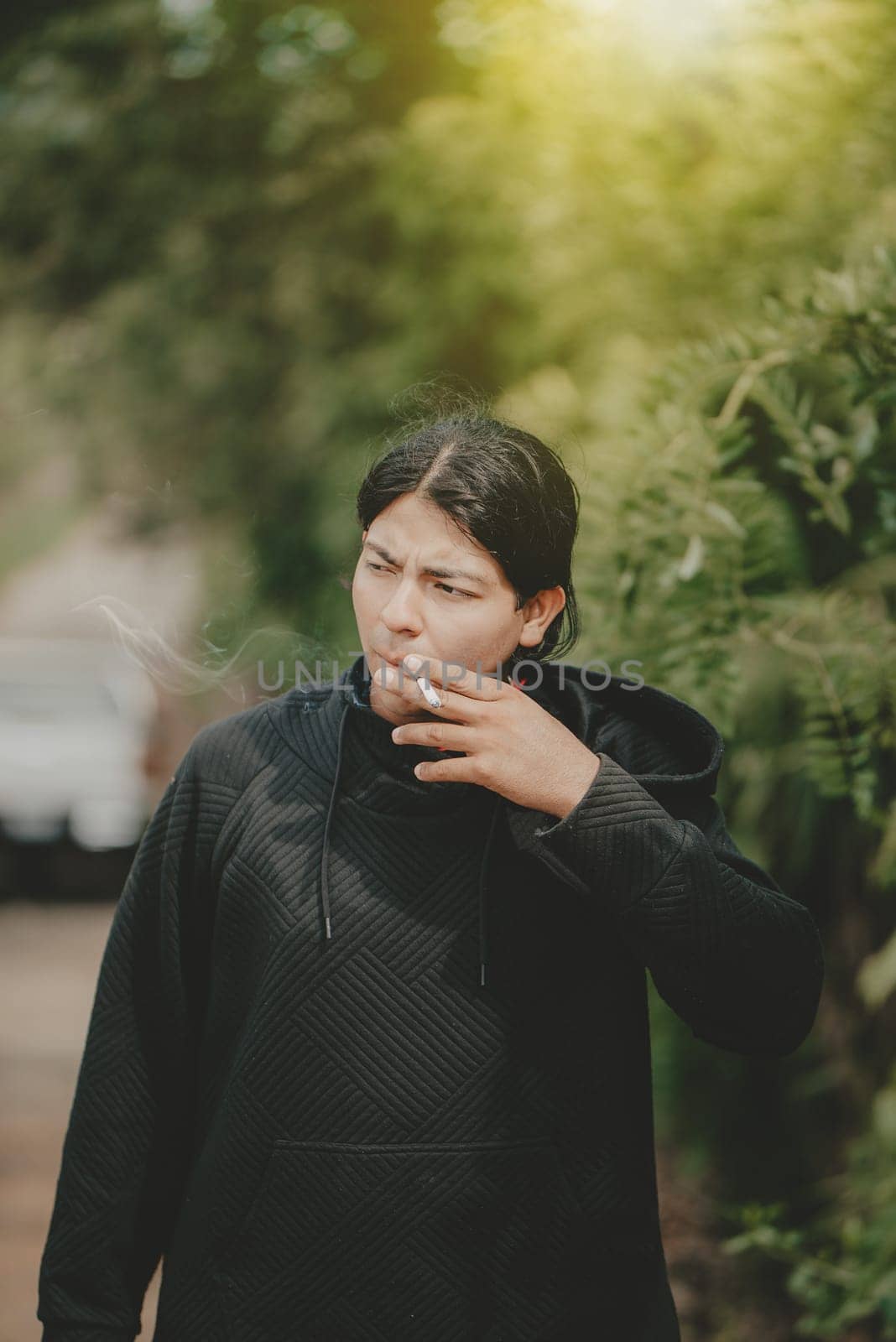 Young man smoking cigarette on the street. Portrait of handsome guy smoking outdoors