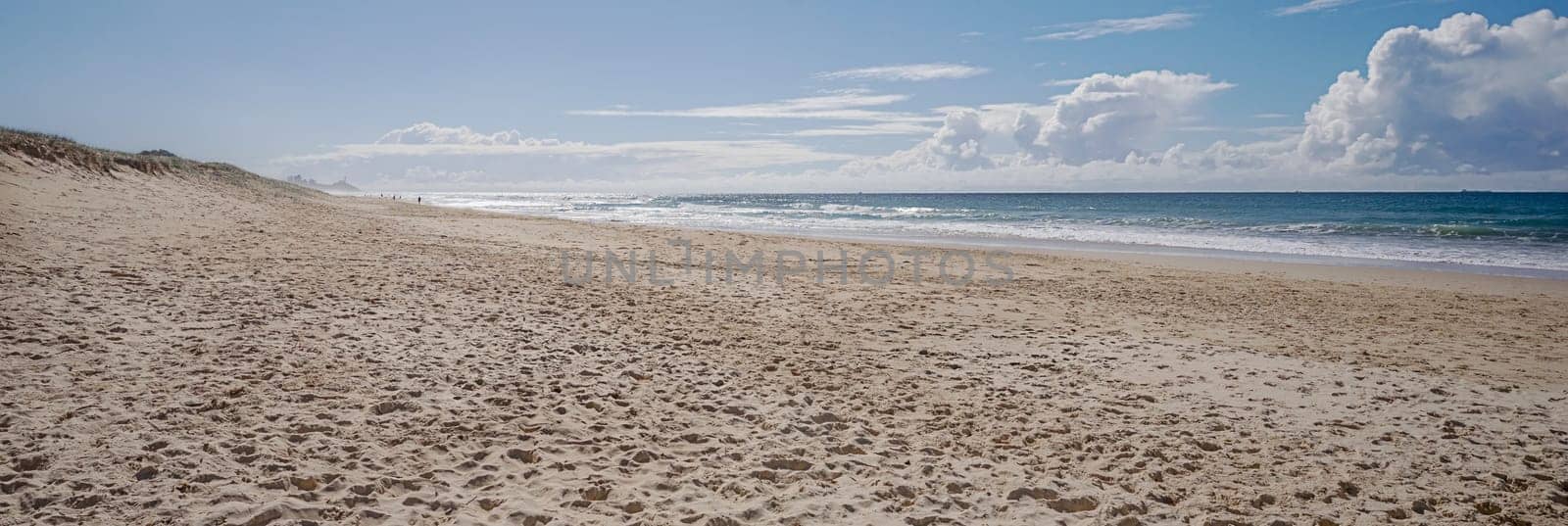 Seascape landscape panoramic view of sandy beach, ocean and straight horizon with lots of footprints in the sandy foreshore