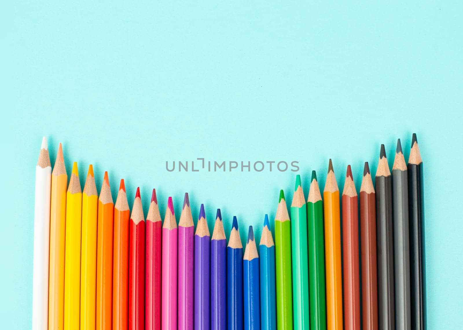 Color pencils collection in a row, back to school, drawing supplies, blue background with copy space
