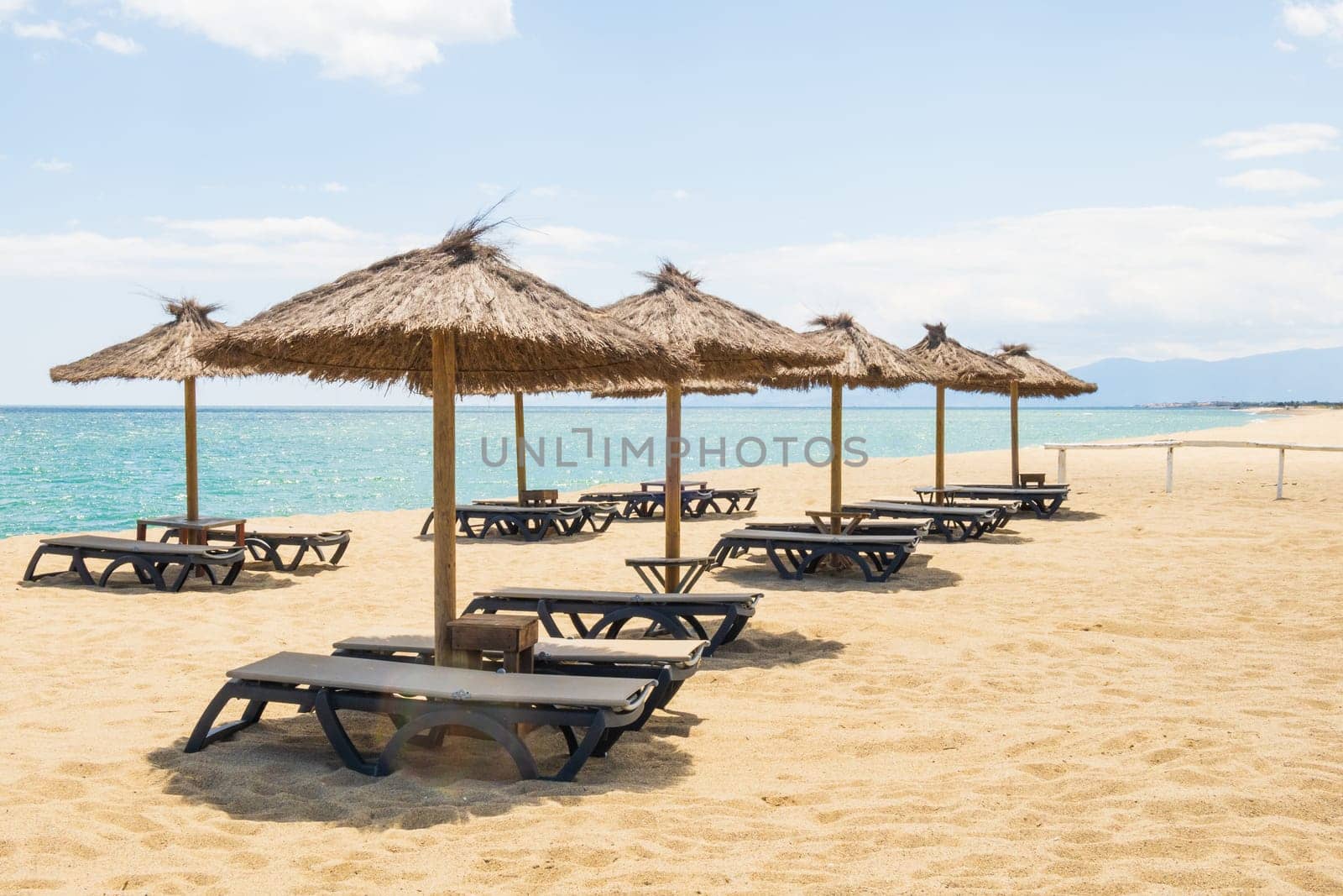 Le Barcarès, France - May 22, 2024: empty sun loungers and beach umbrellas at the coastline of the Mediterranean sea