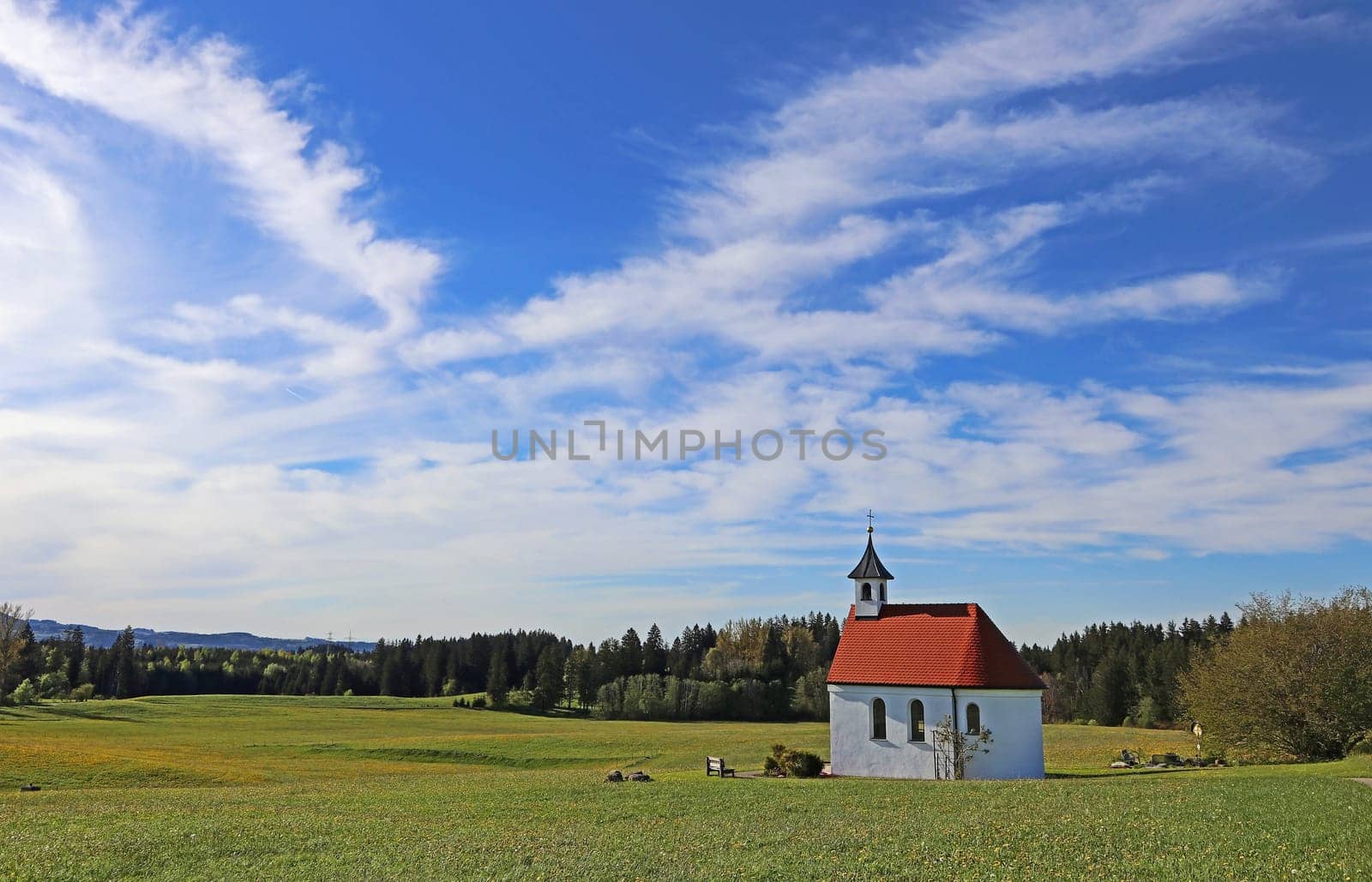 A small chapel in spring under a white-blue sky in the Allgäu