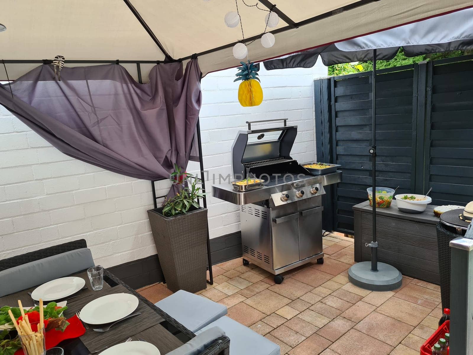 HEILIGENHAUS, NRW, GERMANY - JUNE 30, 2020: Heiligenhaus, Nrw, Germany - Juner 30, 2020: Having fun on the terrace, drinking beers and chatting while their friends serve the meat roasted on the bbq. Shot with flare