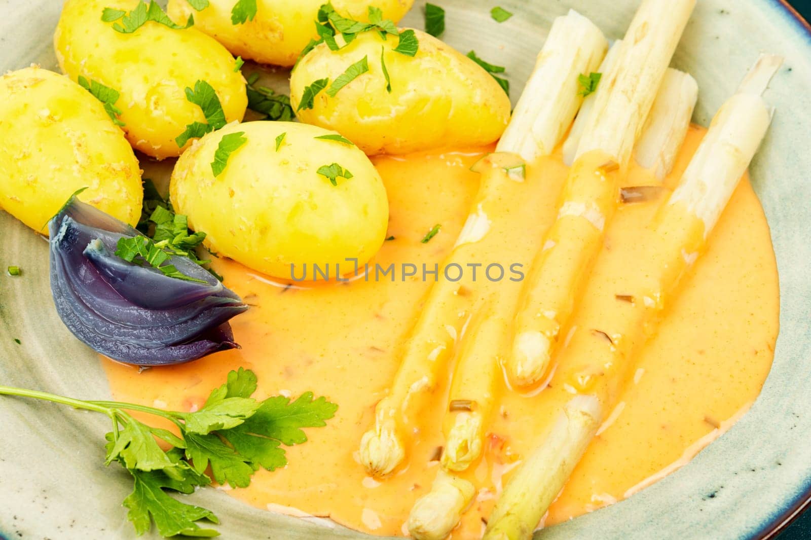 Vegan food, new boiled potatoes and white asparagus on rustic wooden table.