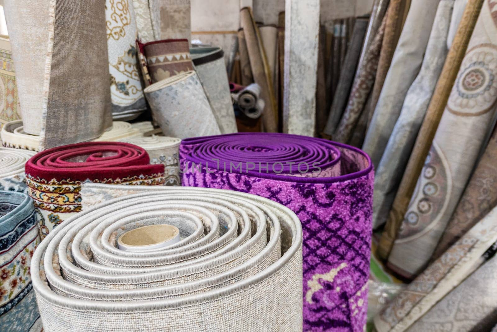 Many rolled carpets in Asian carpet store and carpet warehouse. Full-frame closeup background.