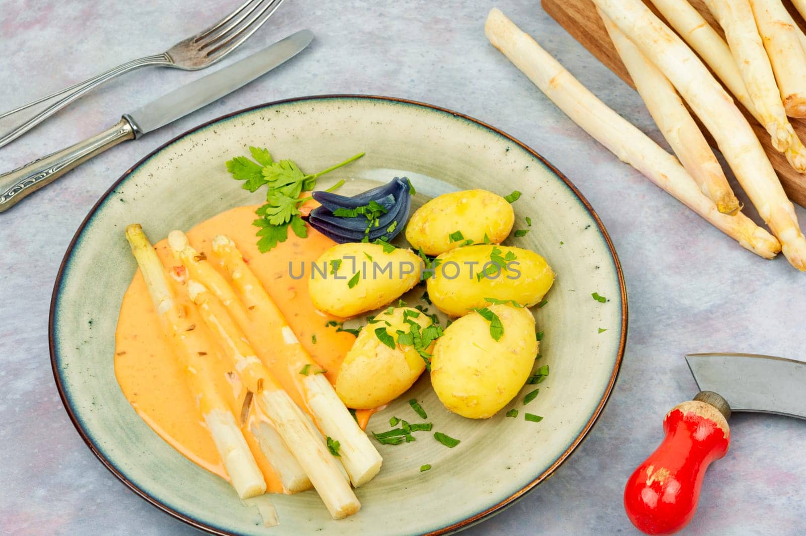 Vegan food, new boiled potatoes and white asparagus on rustic wooden table.