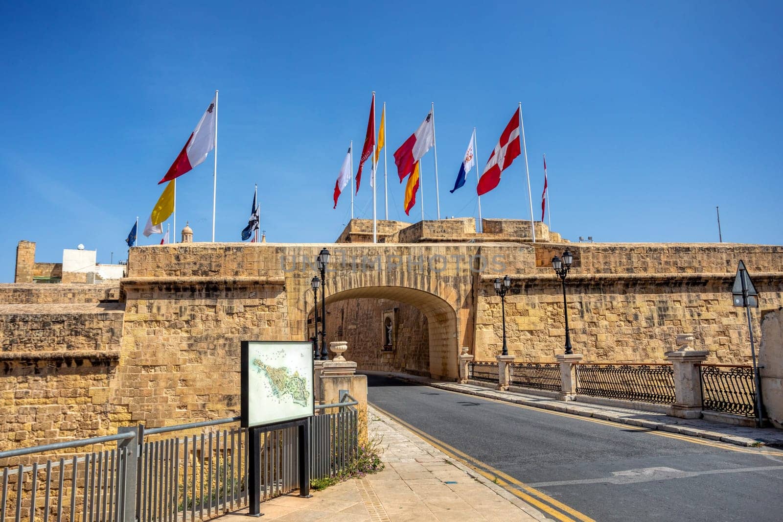 Gate of Provence Birgu and city fortification with Maltese flags. Beautiful view of entrance of ancient city Birgu, part of the Three Cities of Malta. Cultural heritage of Malta