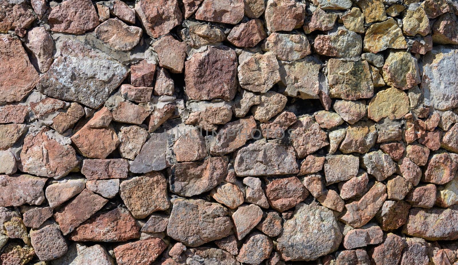 Stone wall background built from a variety of shapes and sizes and fitted together to create a strong and stable structure.