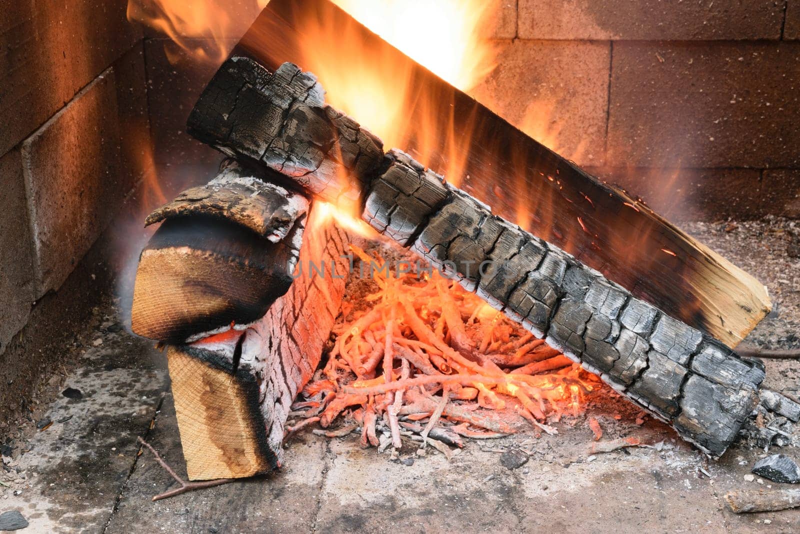 A close-up of burning firewood in a fireplace, with flames and glowing embers.