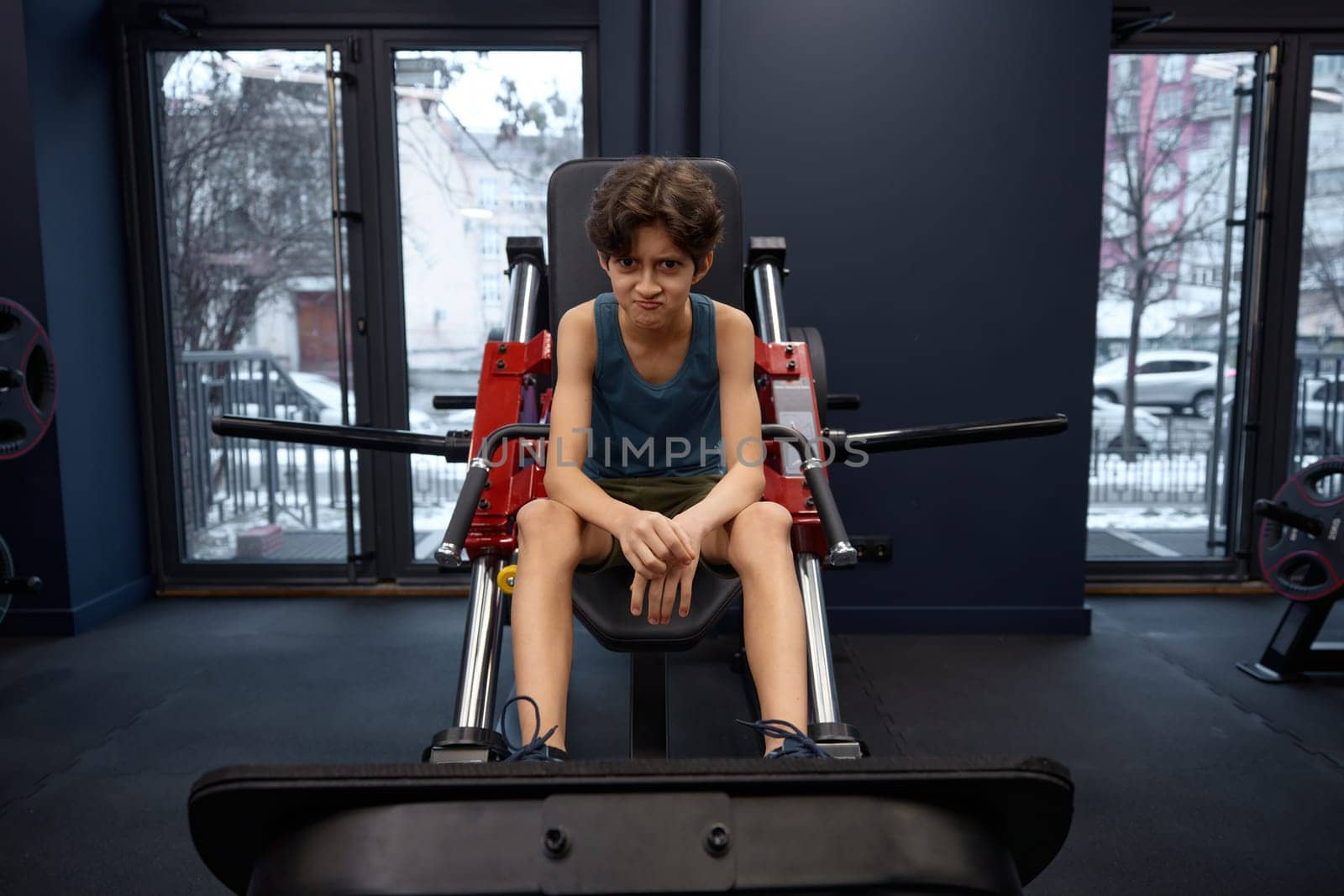 Funny preteen boy athlete during his gym workout. Happy sportive childhood, healthy lifestyle and body training