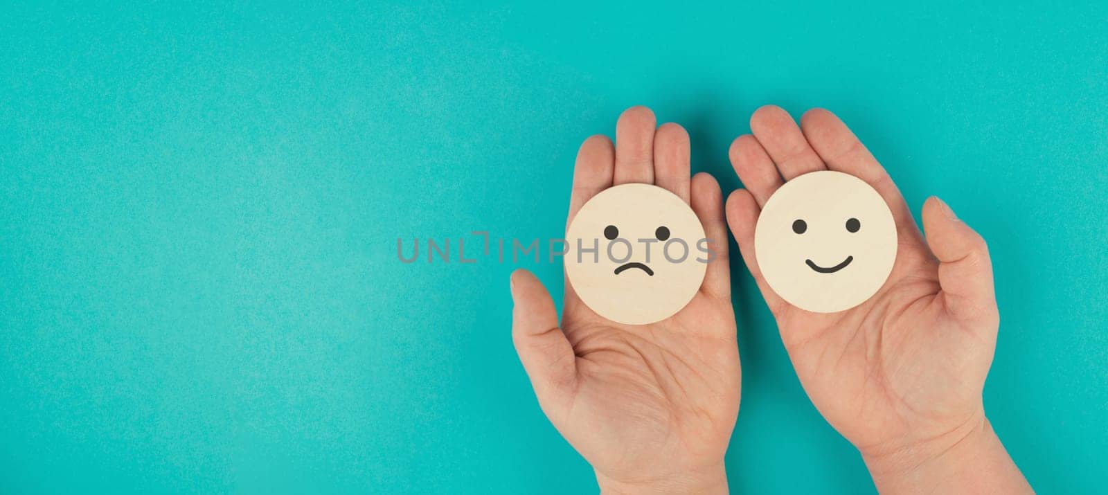 Holding a head with a sad and a happy face in the hands, mental health concept, positive and negative mindset, depression, support and evaluation symbol, emotion