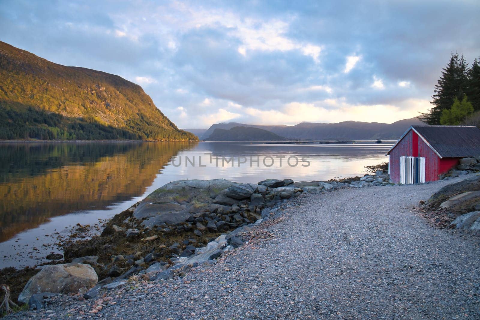 Norwegian landscape. View over a small harbor to the fjord with a cloudy sky behind the mountain. Scandinavian nature