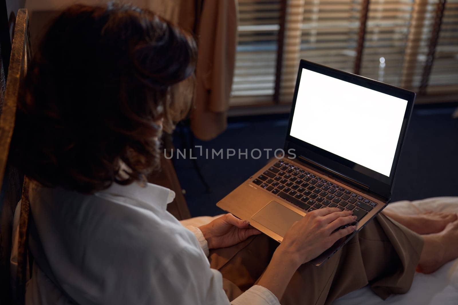 Businesswoman working online using laptop while resting with comfort and tranquility in bed at hotel room