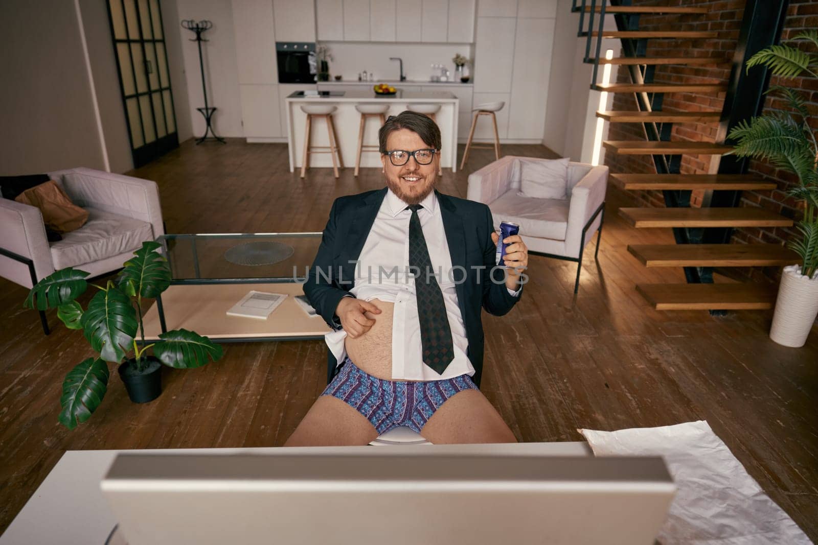 High angle view on funny businessman scratching belly drinking energetic beverage taking break, having rest time during online work at comfortable home office