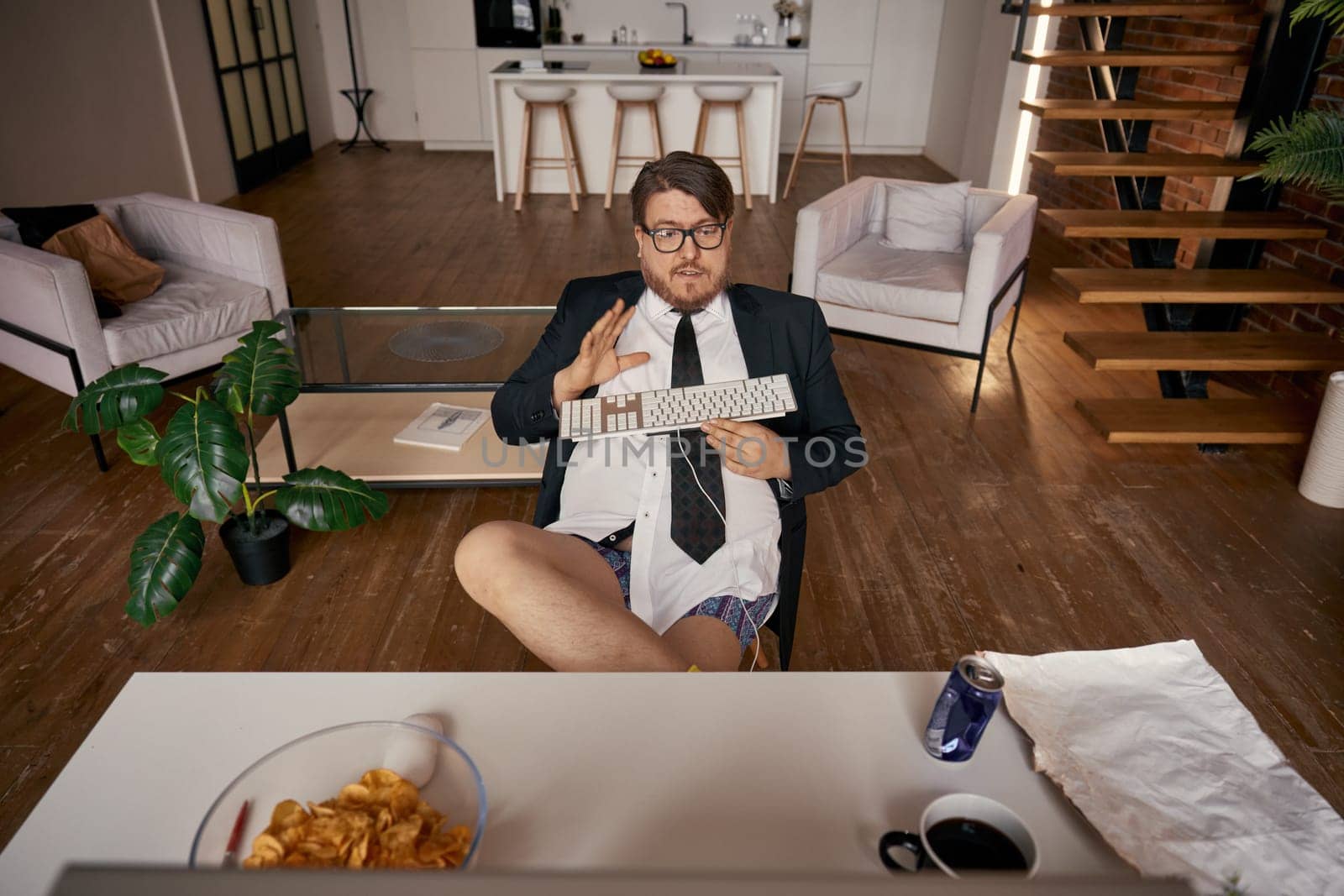 Lazy relaxed funny businessman feeling excitement working online comfortably holding pc keyboard on fatty belly high angle view. Freelance job, self-employment, work convenience and accessibility