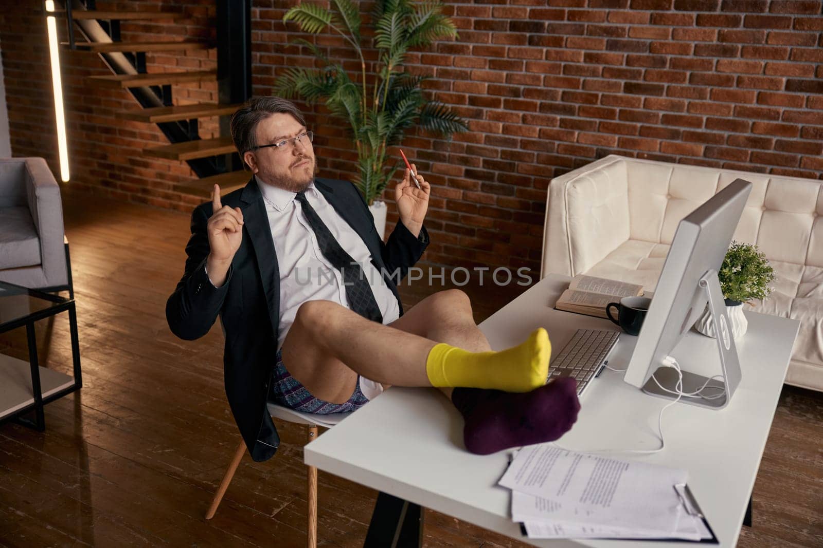 Funny businessman wearing formal suit put his legs on the desk working online. Male entrepreneur feeling extremely impressive reading e-mail with shock news on computer screen