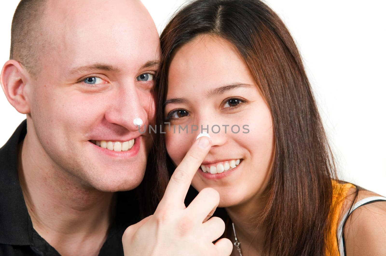 Head and shoulder portraits of a young couple with dabs of cream on their noses looking happily into the camera.