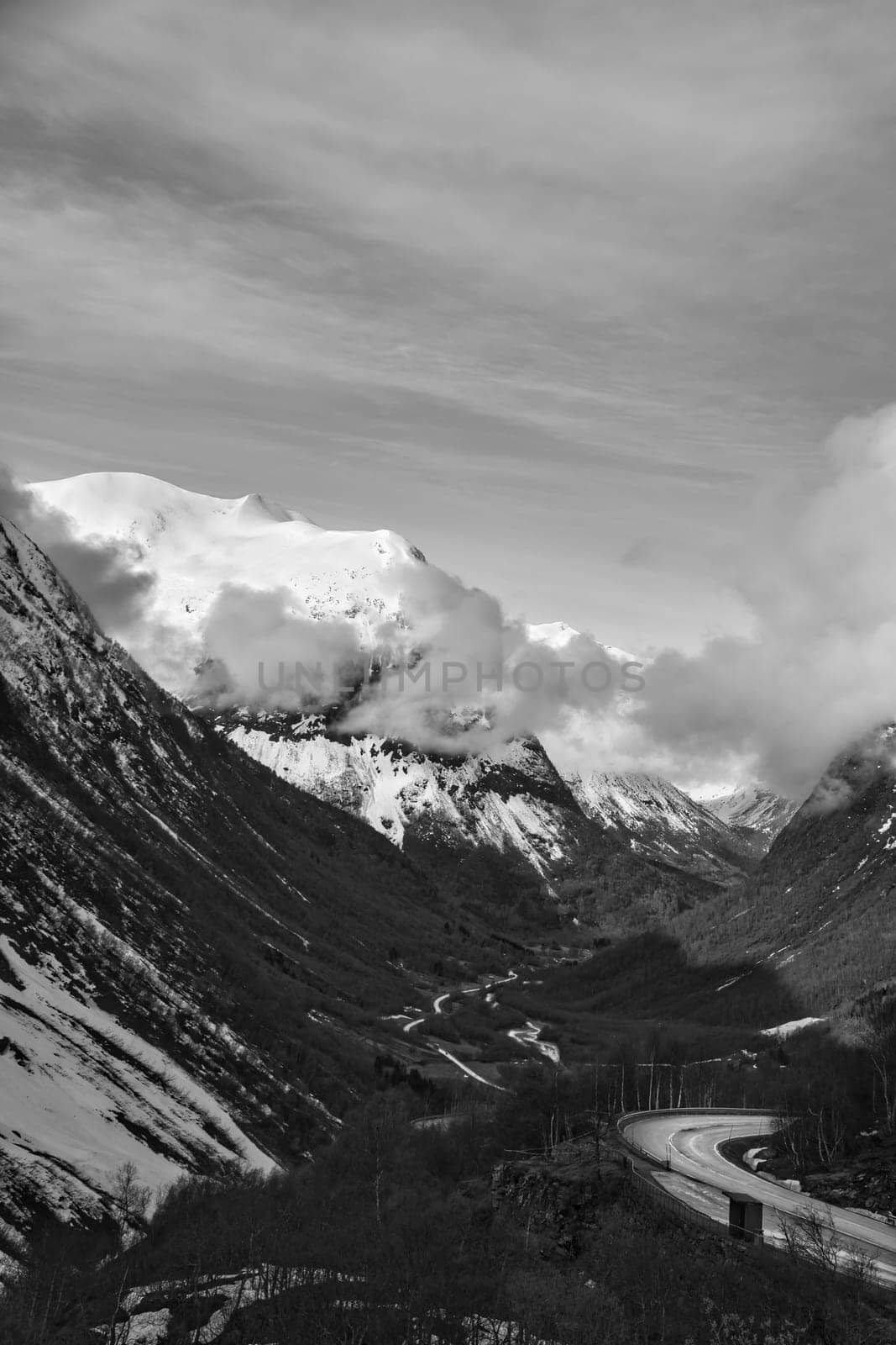 Norwegian landscape. Road leads through a mountain gorge that descends from the glacier in black and white. Rough nature in Scandinavia. Landscape photo from the north