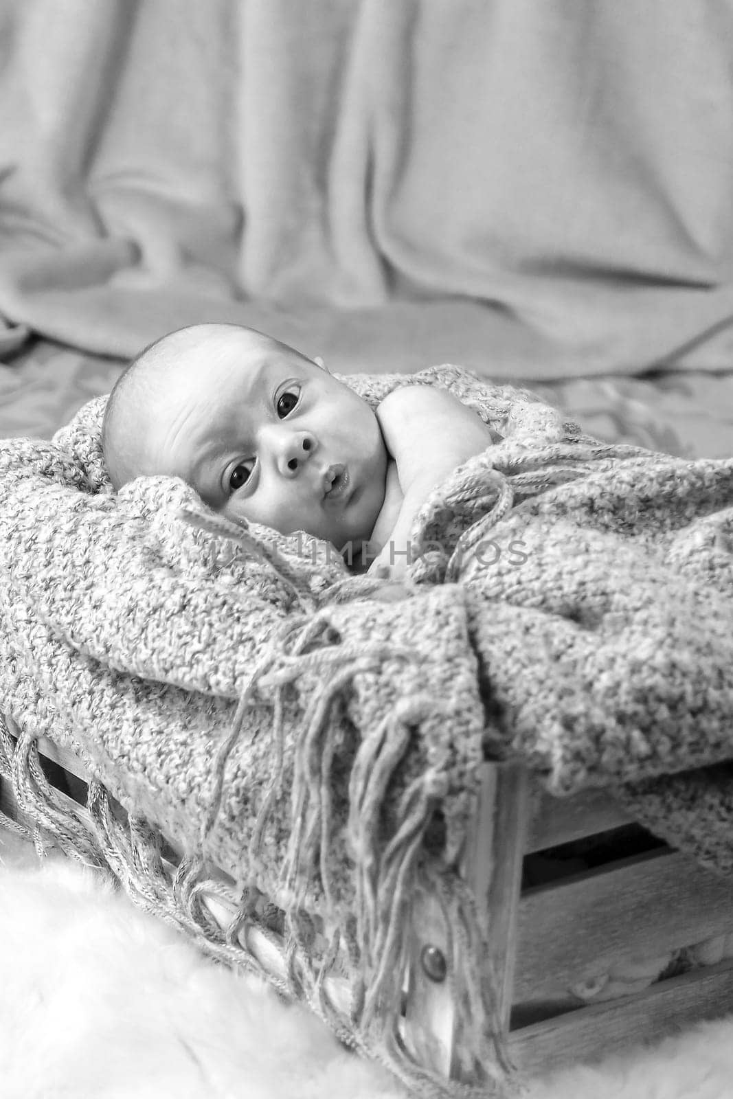 Black and white photo of a newborn with an emotional expression on his face. Selective focus with shallow depth of field.