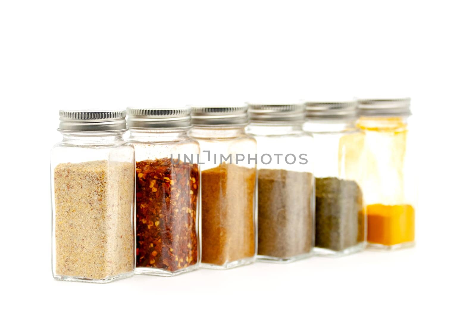 Square glass jars for storing dry kitchen spices. Selective focus with shallow depth of field.