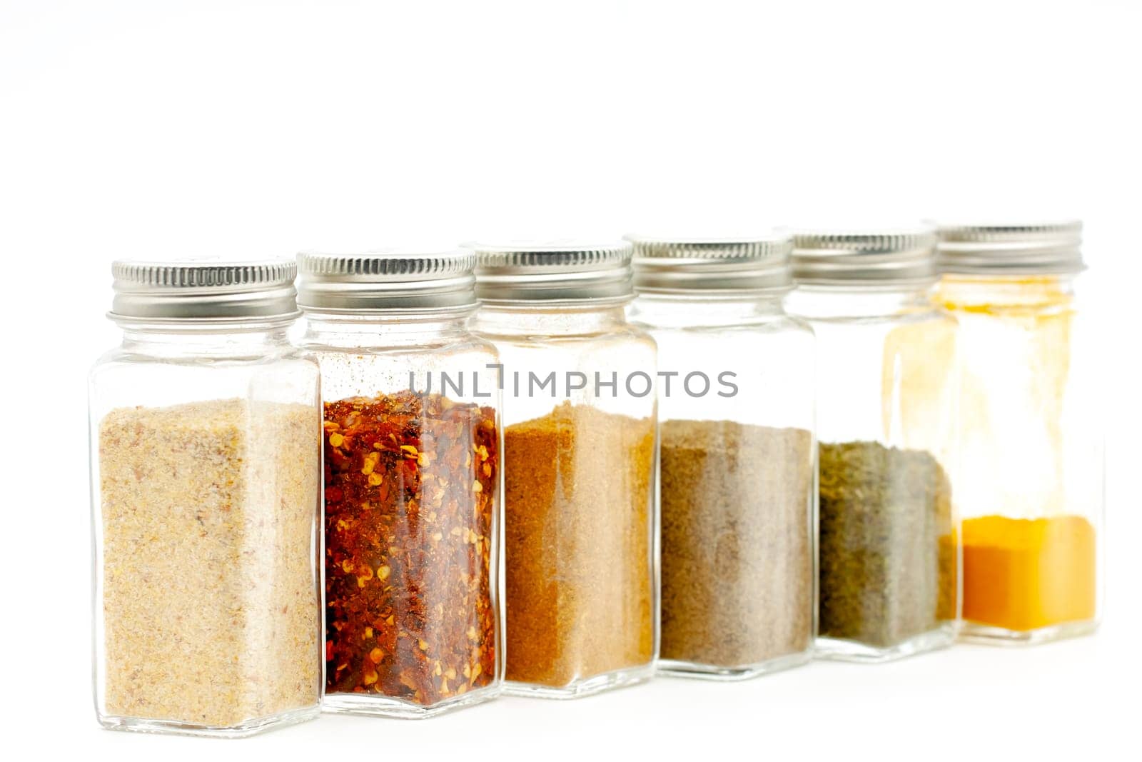 Square glass jars for storing dry kitchen spices. Selective focus with shallow depth of field.