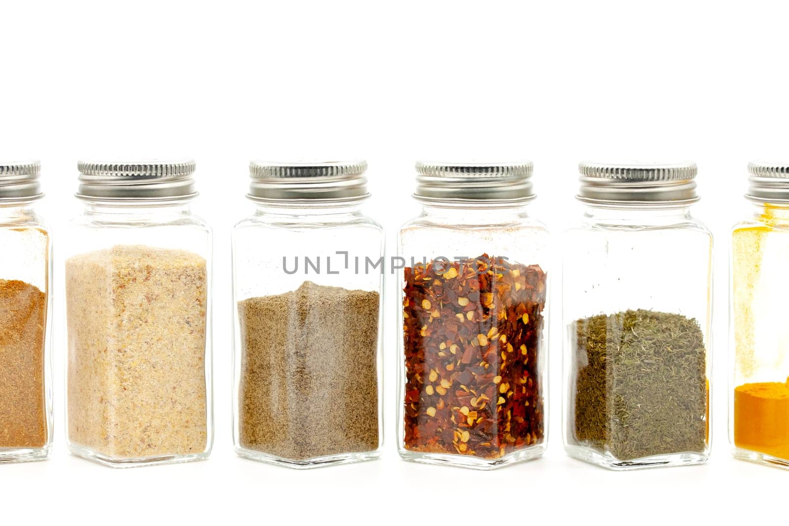 Square glass jars for storing dry kitchen spices. Selective focus with shallow depth of field.