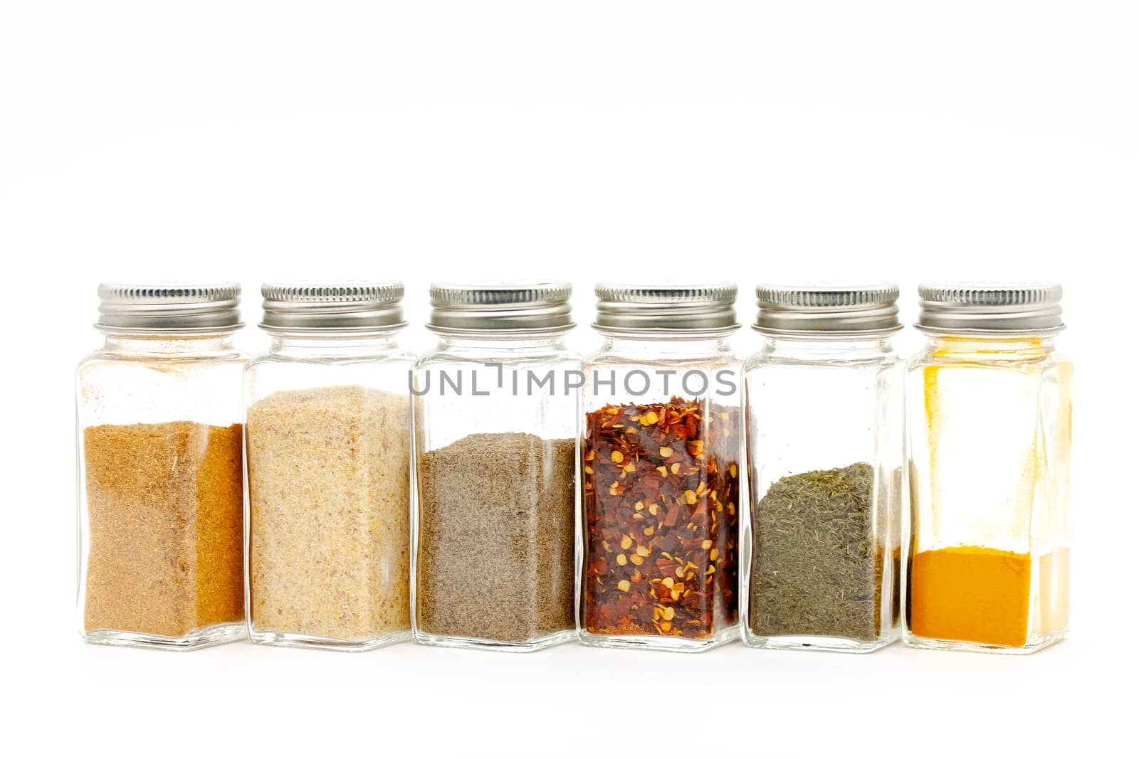 Square glass jars for storing dry kitchen spices. Selective focus with shallow depth of field.