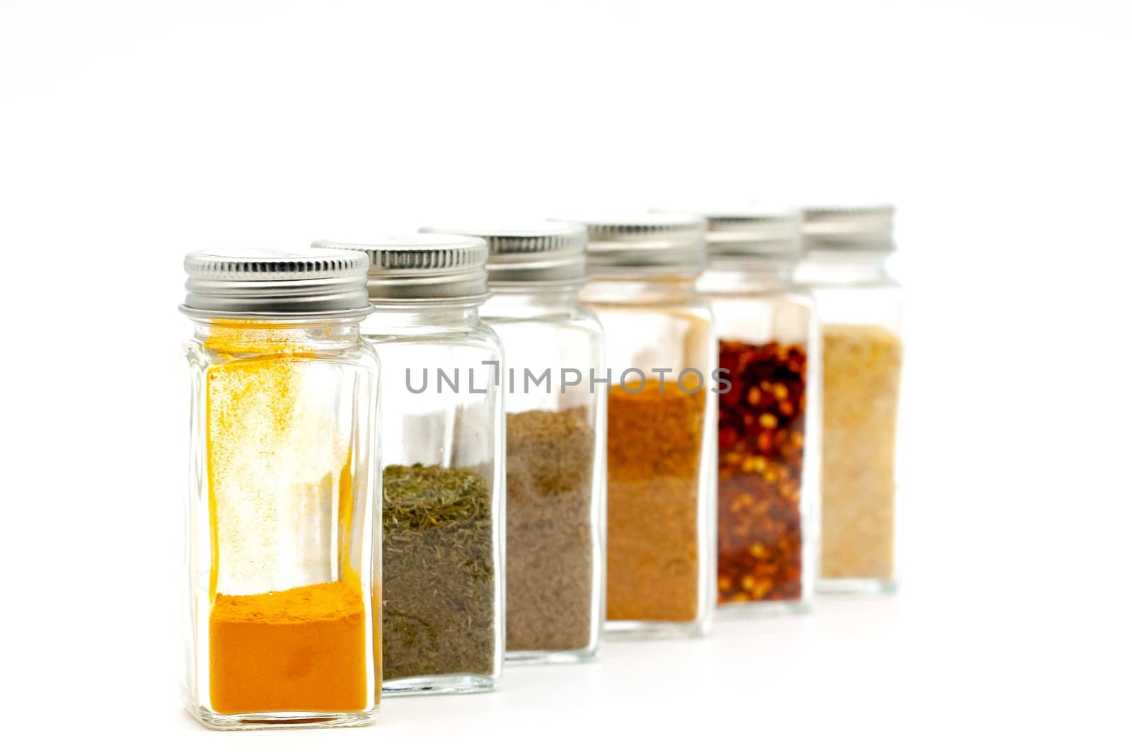 Square glass jars for storing dry kitchen spices. Selective focus with shallow depth of field.