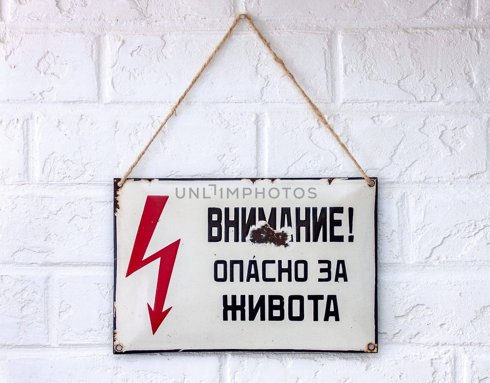 An old rusty enamelled Cyrillic sign warning of danger from an Eastern European country.