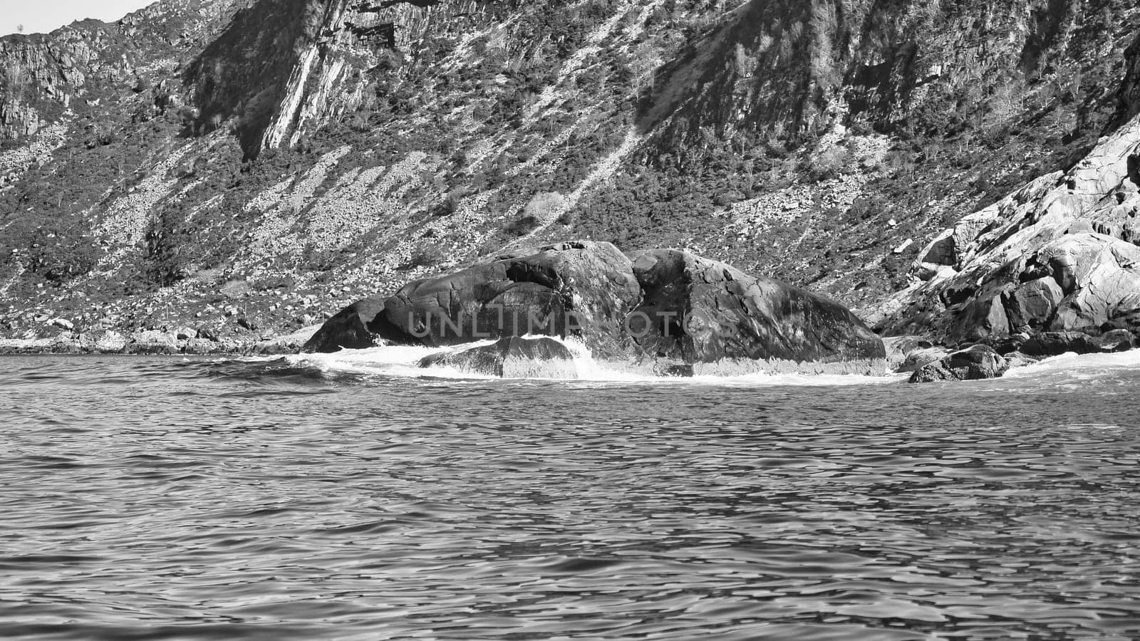 Norwegian fjord landscape. Waves crash against rocks in black and white. Water splashes against the rock. Landscape in Scandinavia