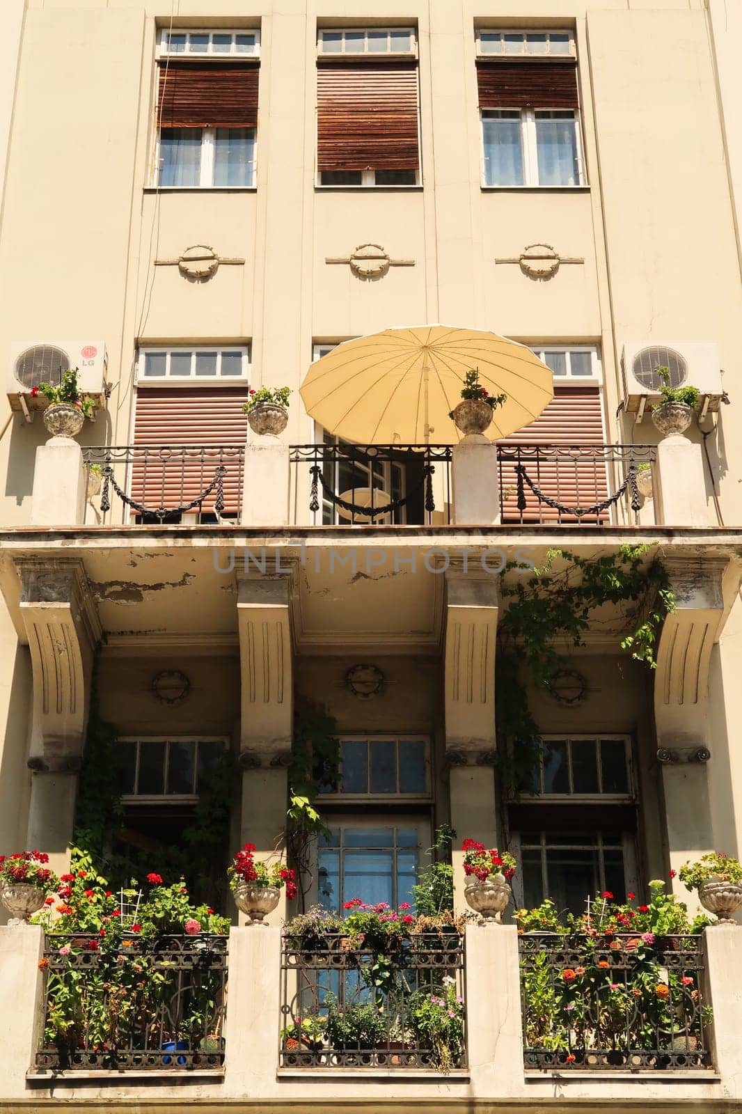Beautiful balconies with green plants and an umbrella on the facade of an old neoclassical house, building close to the Knez Mihailova, Knez Mihaila Street in the city center of Belgrade, Serbia 2022