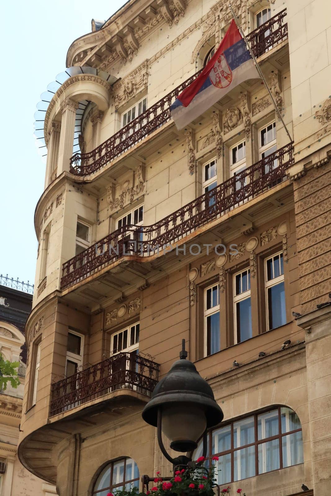 The elaborate facade of the Serbian Academy of Sciences and Art with a Serbian Flag on it, an example of Art Nouveau architecture in the city center of Belgrade, Serbia 2022