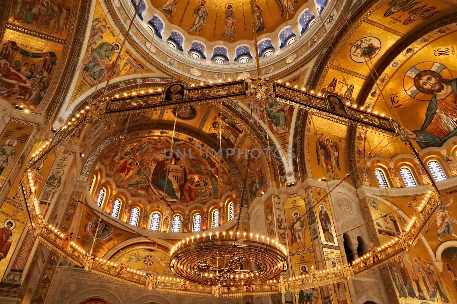 The big golden Chandelier inside of the Church of Saint, St. Sava, golden walls, vaults, ceiling covered in mosaics in the background, Belgrade, Serbia 2022