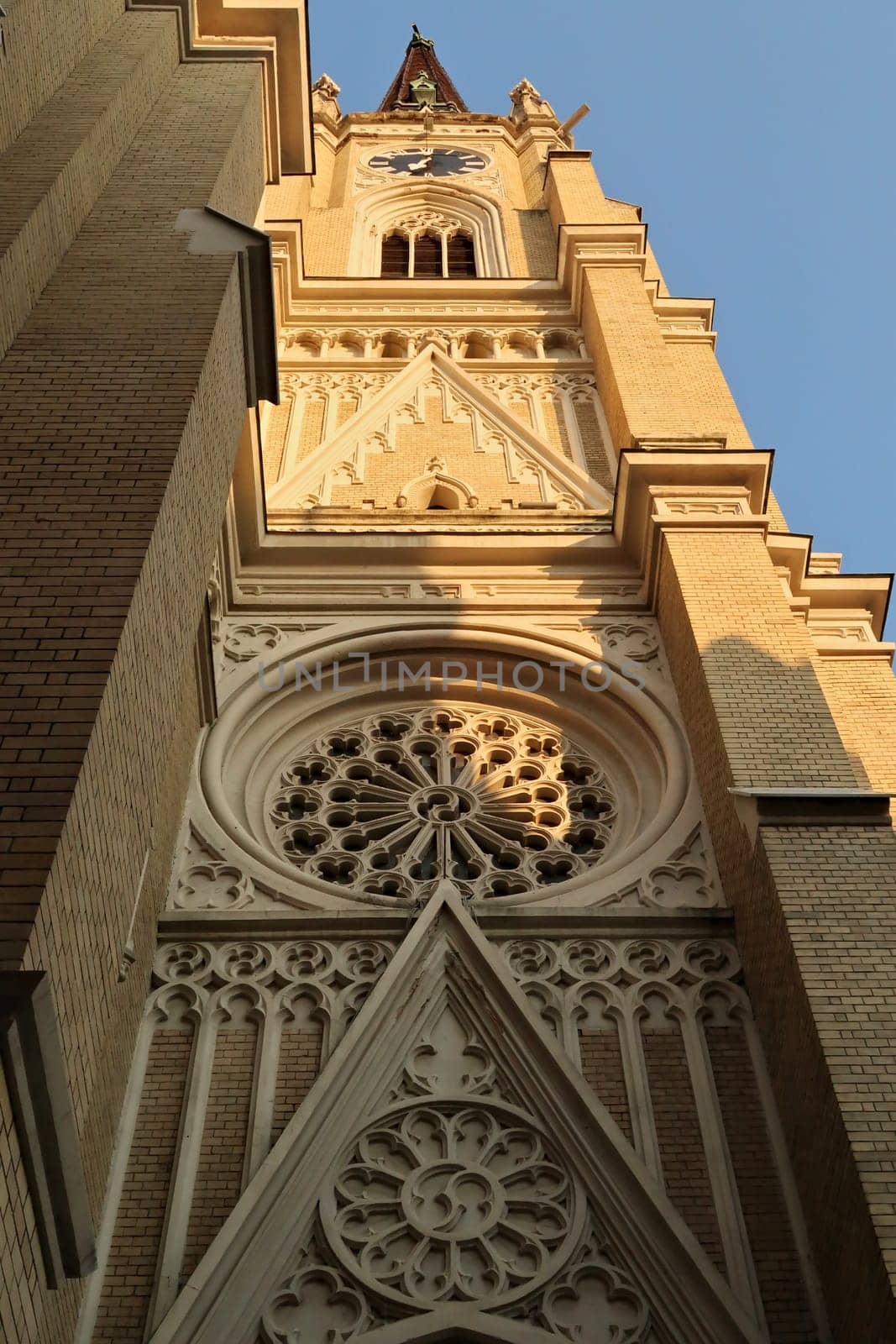 Closer look onto the elaborate facade of the bell, clock tower of the Name of Mary Church, an example of neo-gothic architecture in the city center, old town of Novi Sad, Serbia 2022