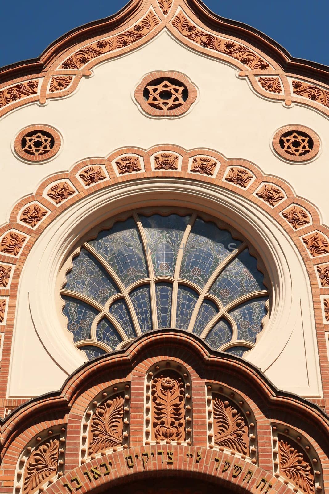 The upper front facade above the entrance of the Synagogue of Subotica, a big stained glass window is surrounded by elaborate details, stucco, carvings, patterns, ornaments, Subotica, Serbia 2022