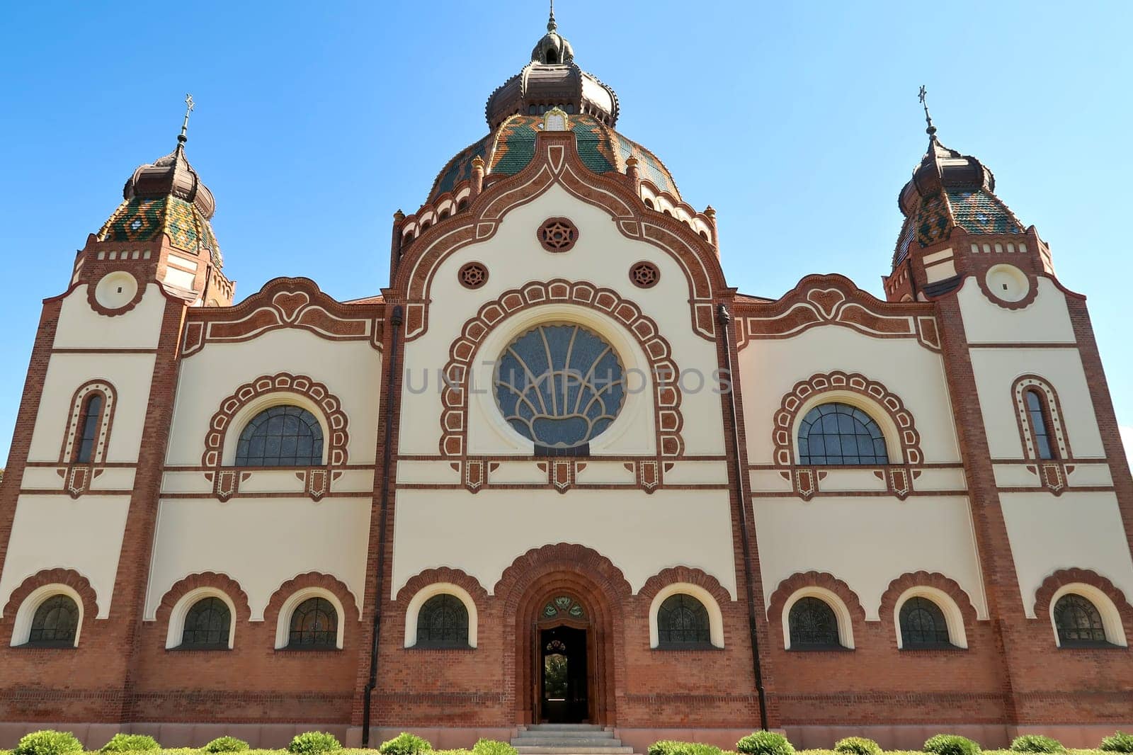 The complete facade around the side entrance of the Synagogue of Subotica on a sunny day with blue sky and white clouds, Subotica, Serbia 2022