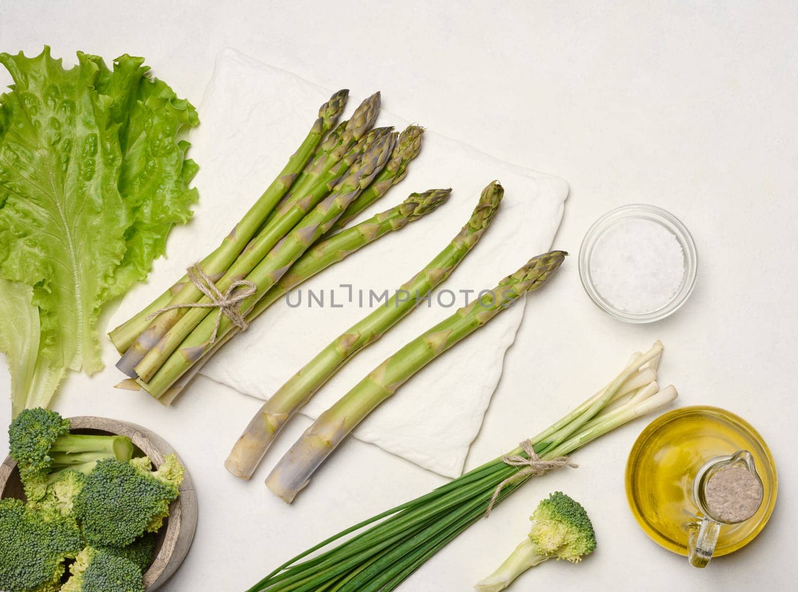 Raw asparagus, broccoli and spices on white background, top view
