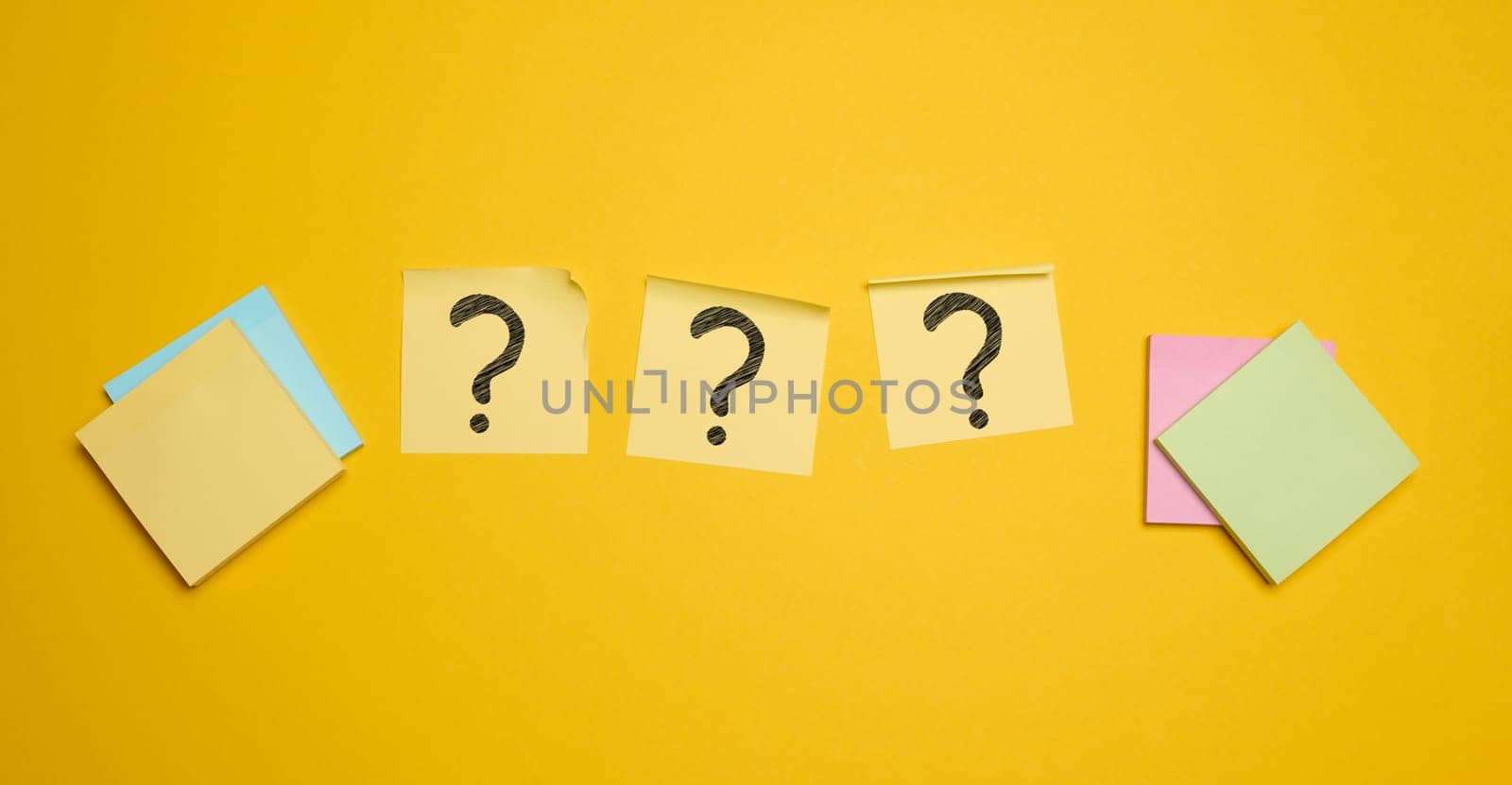 Drawn question marks on stickers, yellow background. Searching for truth and answering questions