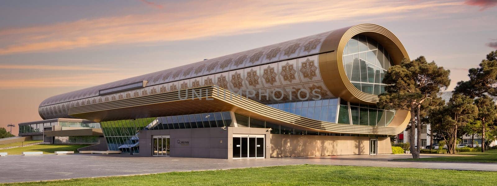 Sunset shot of the Azerbaijan National Carpet Museum in Baku showcases innovative architecture, featuring large windows and a unique rolled carpet design