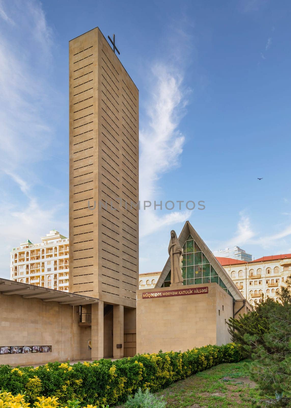 An exterior view of the Neo-Gothic style Church of the Immaculate Conception in Baku, Azerbaijan, featuring a tall tower and a statue of the Virgin Mary
