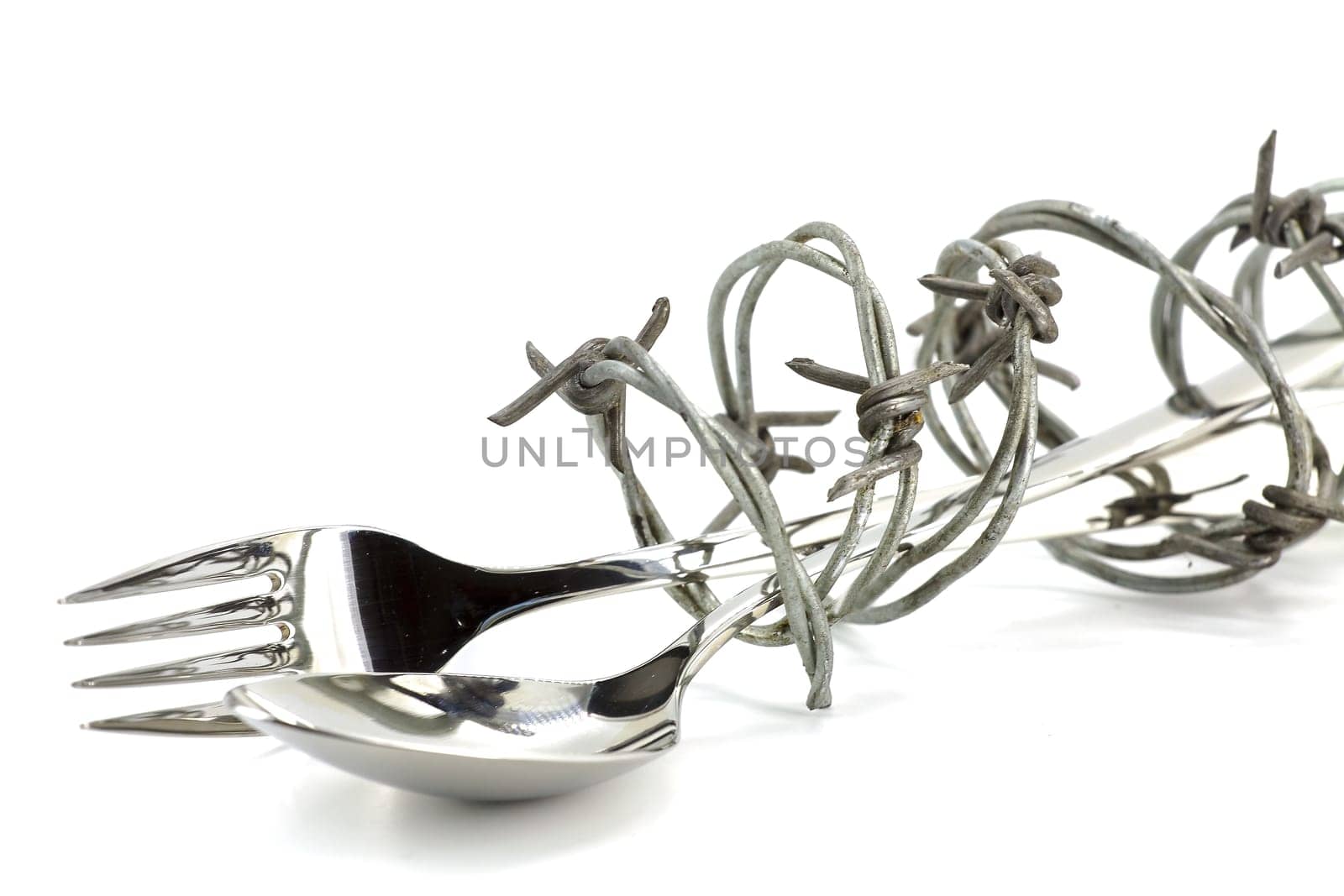 Barbed wire around fork and spoon on white background