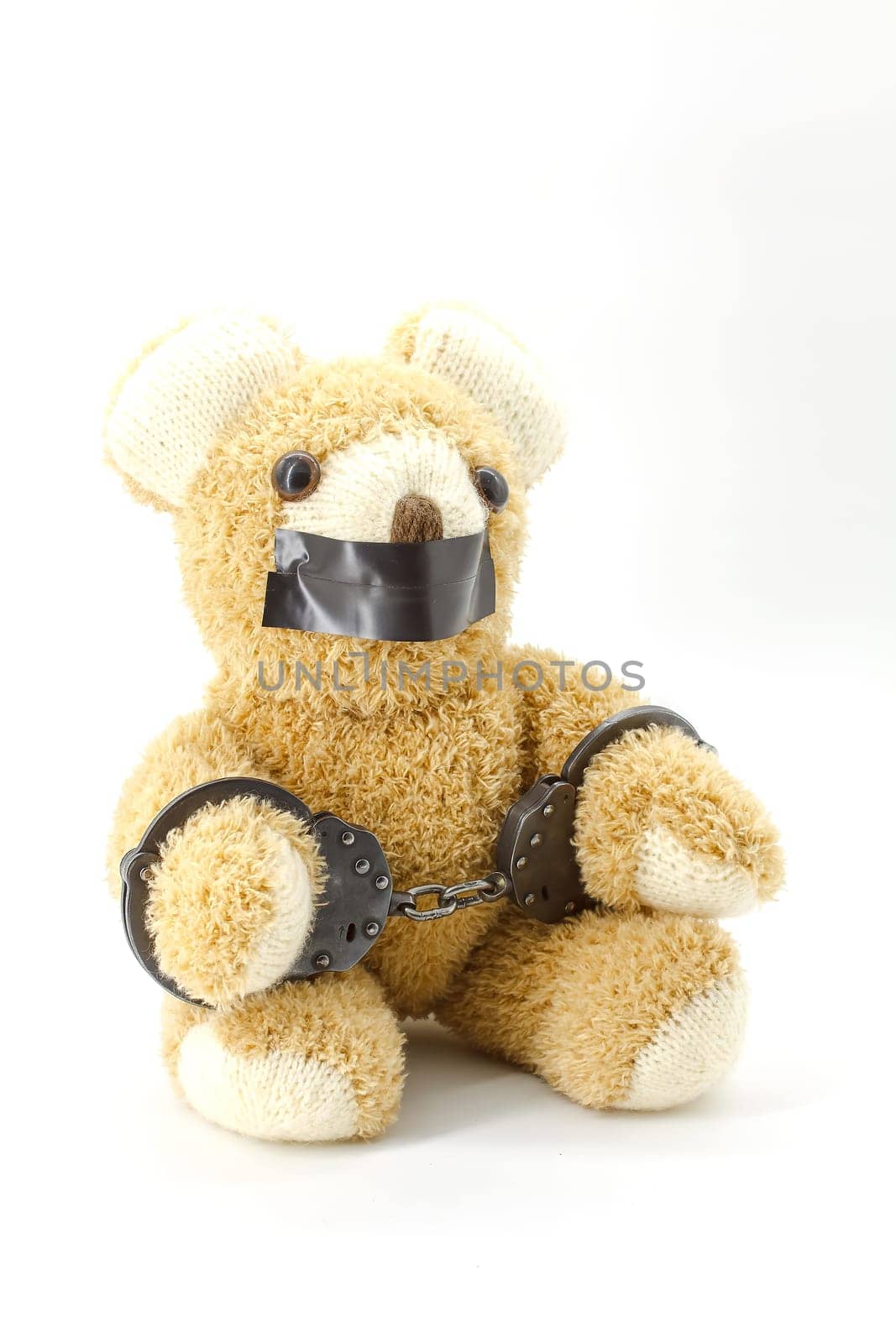 Plush teddy bear with handcuffs on white background